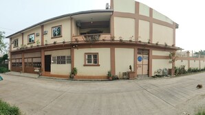 A two-story building with a balcony, potted plants, and a sign indicating a business. - Villa Elsie Resort and Hotel (General Trias)