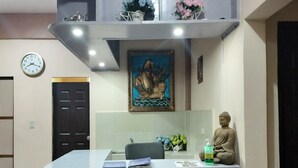 A reception desk with a clock, a Buddha statue, and a painting above it. - Villa Elsie Resort and Hotel (General Trias)