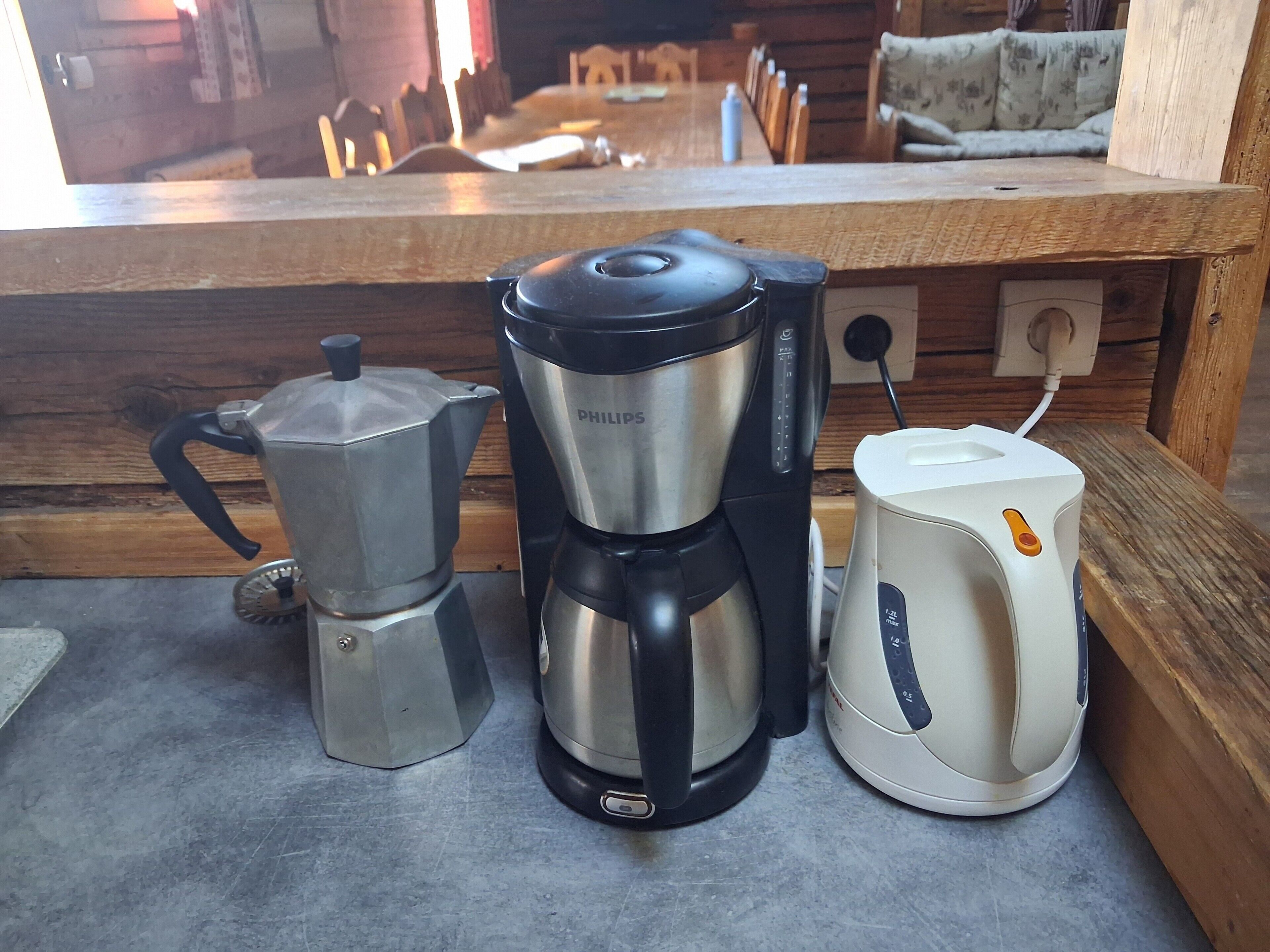 A kitchen counter with a coffee maker, a coffee pot, and a kettle.