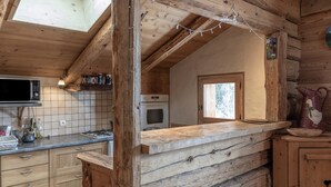 Una cocina rústica con leña, un microondas y una estufa.
