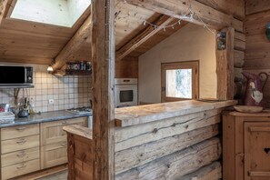 A rustic kitchen with wooden logs, a microwave, and a stove.