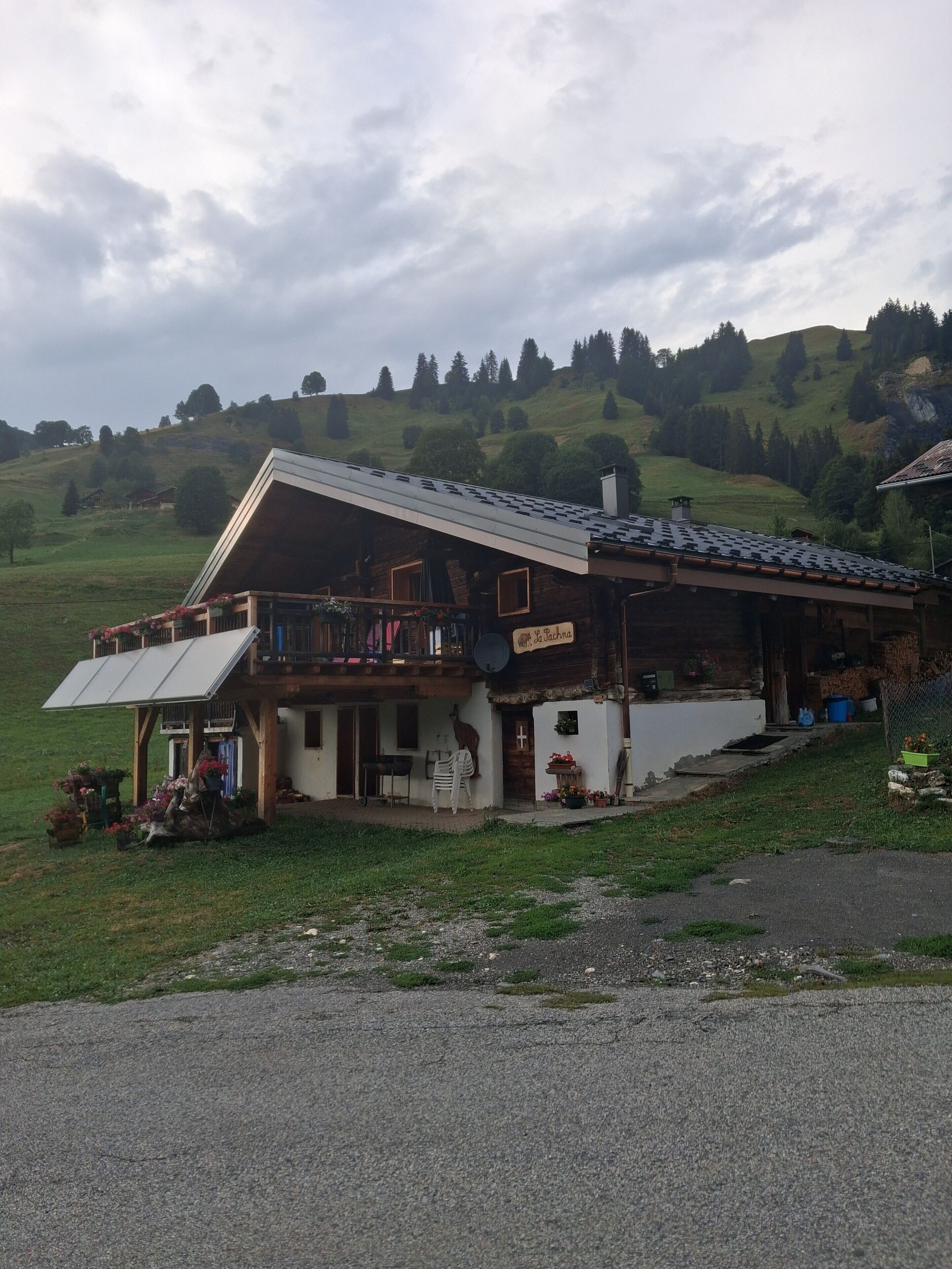 A chalet with a balcony, a sign indicating a restaurant, and a view of a green hillside.