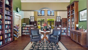 A spacious library with leather chairs, a round table, and a large window. - 8209 Bibiana Way 403 (Fort Myers)