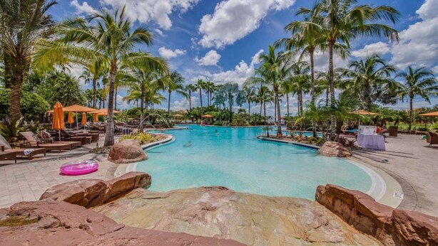 A large outdoor swimming pool surrounded by palm trees and lounge chairs. - 8209 Bibiana Way 403 (Fort Myers)