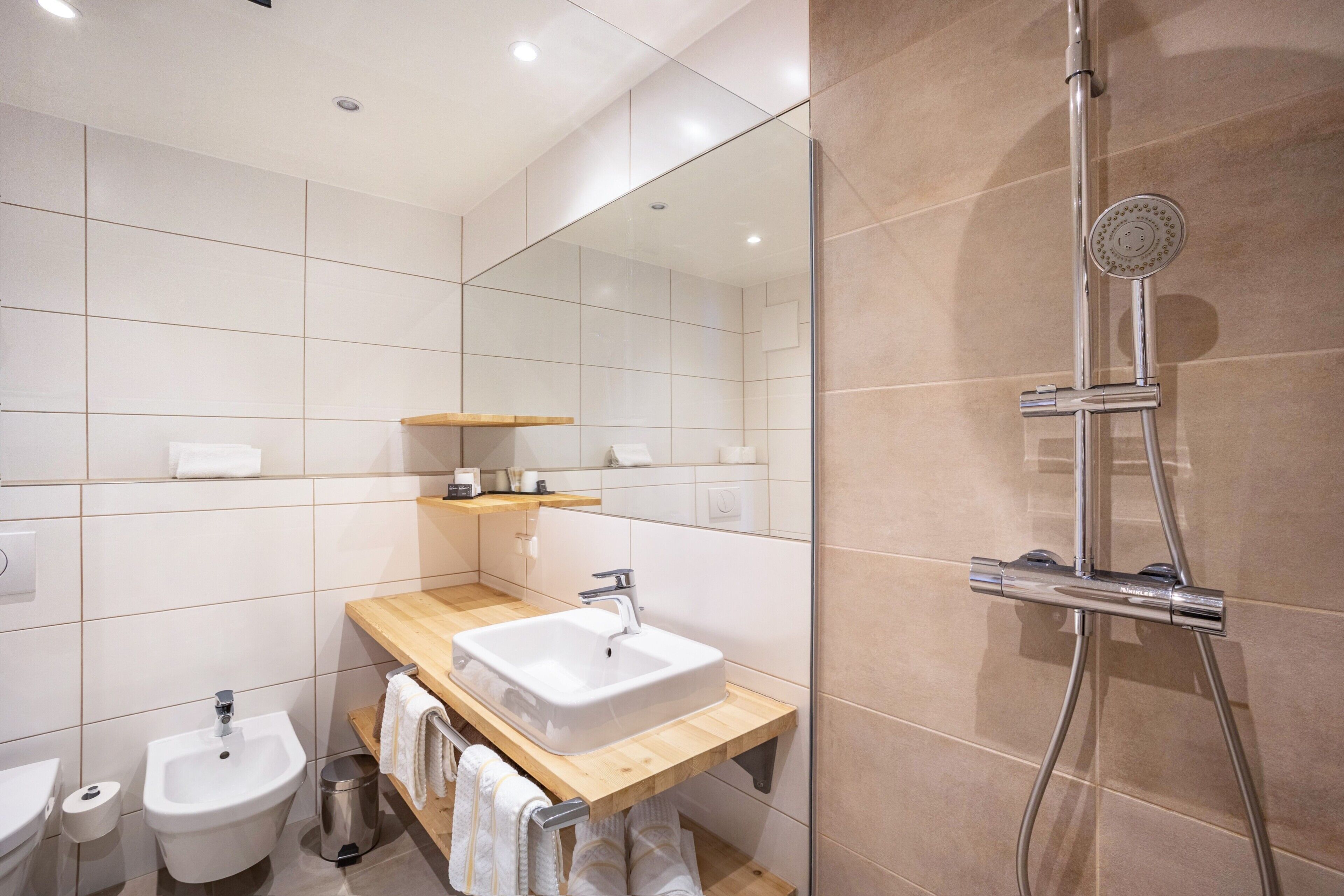 A modern bathroom with a sink, bidet, and shower.