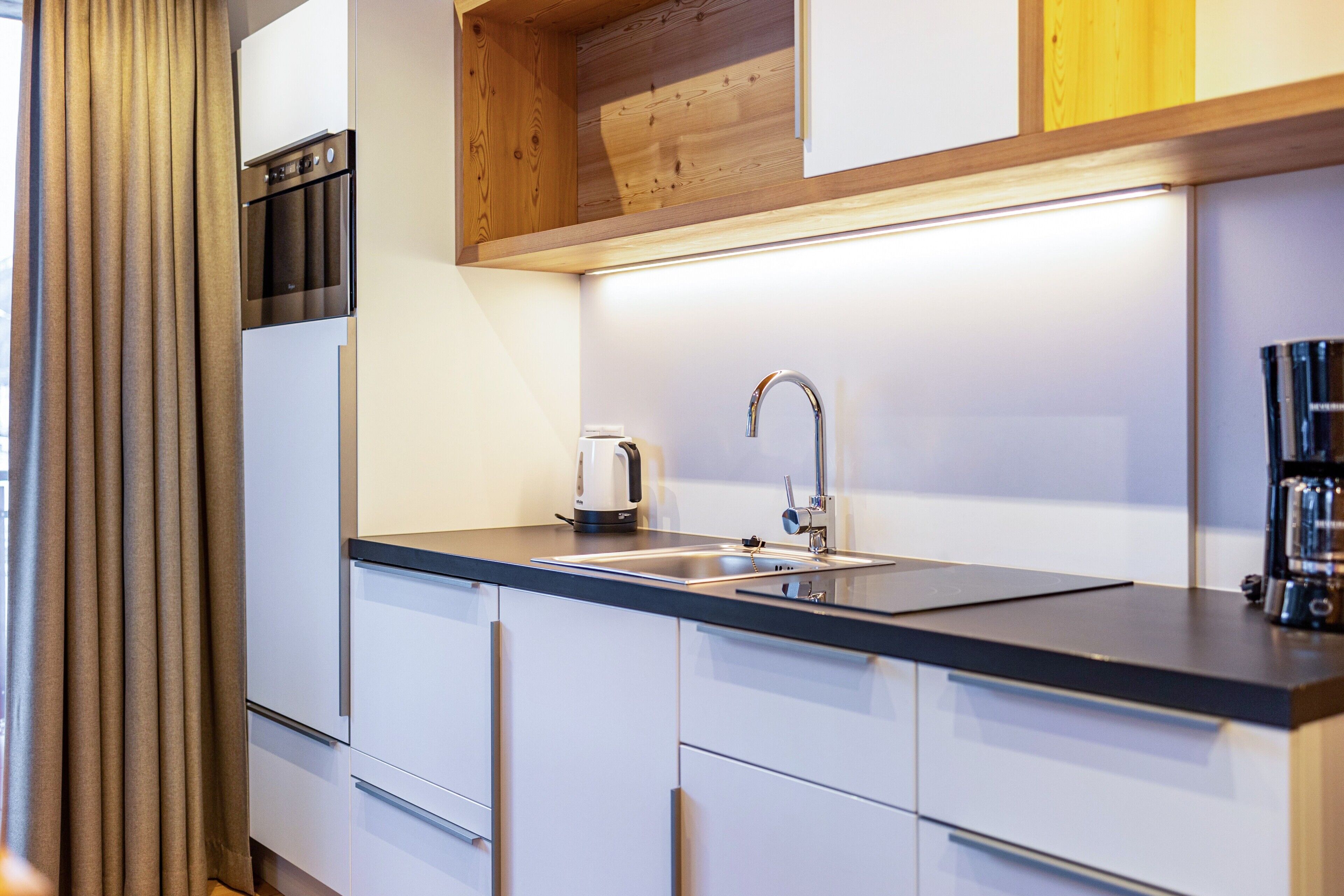 Een moderne keuken met een ingebouwde oven, een spoelbak en een koffieapparaat.