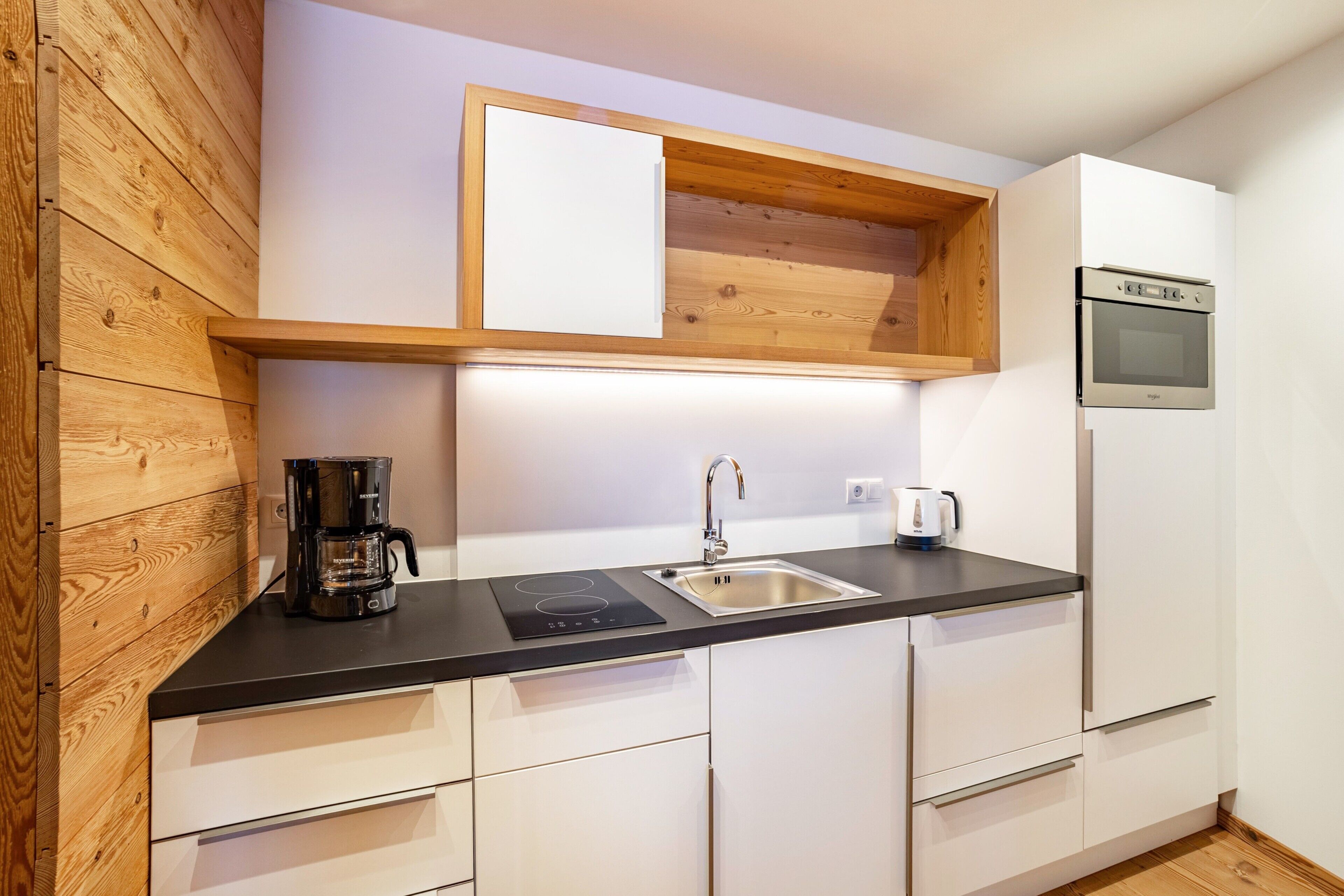 A modern kitchen with a built-in oven, a coffee maker, and a sink.