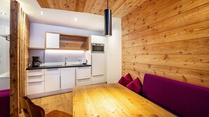 A modern kitchen with white cabinets, a wooden ceiling, and a black pendant light. - Holiday Apartment "Stoana 2-2" with Relaxing Wellness Area (Valle Aurina)
