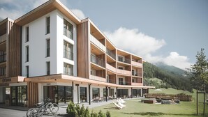 Et hotel med flere etager, balkoner, udendørs siddepladser og udsigt over det omkringliggende landskab.
