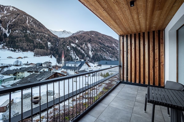 A balcony with a view of a snowy mountain landscape, a wooden ceiling, and a metal railing.