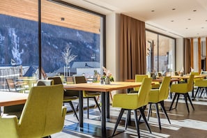 A modern dining area with large windows, wooden tables, and yellow chairs. - Holiday Apartment "Stoana Apt 3-2" with Relaxing Wellness Area (Valle Aurina)