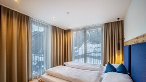 A bedroom with a wooden bed, large windows, and a view of a snowy landscape.