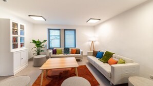 Una sala de estar moderna con un sofá, sillones, una mesa de centro y una estantería.