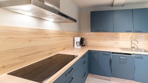 Una cocina moderna con encimera de madera, armarios azules, estufa integrada y cafetera.