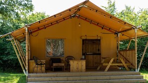 A wooden cabin with a covered porch, a dining table, chairs, and a large painting on the wall.