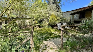 A rustic outdoor area with a gravel path, wooden fence, and a stone building. - Farmhouse "Gufo" with Shared Pool, Private Terrace & Wi-Fi (Pitigliano)