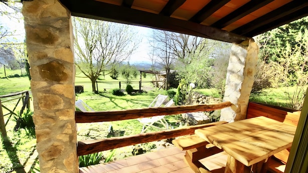 A stone-framed outdoor seating area with a wooden table and chairs, overlooking a grassy landscape with trees and a distant mountain range. - Farmhouse "Gufo" with Shared Pool, Private Terrace & Wi-Fi (Pitigliano)