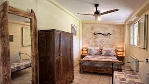 A bedroom with a bed, a wardrobe, a ceiling fan, and a stone wall. - Farmhouse "Gufo" with Shared Pool, Private Terrace & Wi-Fi (Pitigliano)