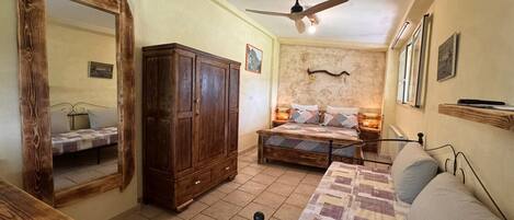 Quarto com cama, guarda-roupa, espelho, ventoinha no teto e janela.