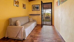 A room with a sofa, a tiled floor, a wooden ceiling, and a door leading outside. - Farmhouse "Sasso Bianco" with Shared Pool, Private Terrace & Wi-Fi (Pitigliano)