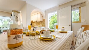 Ein Esstisch mit einer Mandarinen-Saftflasche, einer Tasse, einem Glas und einem Teller mit Essen.