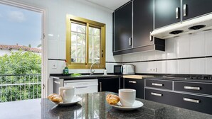 Eine moderne Küche mit schwarzen und weißen Schränken, einem Fenster mit Blick auf Grünflächen und zwei Tassen mit Croissants auf der Arbeitsplatte.