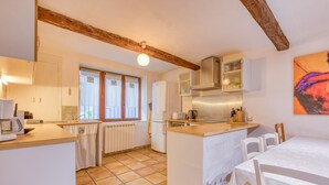 Une cuisine dotée d’un îlot central, de meubles blancs et d’un coin repas avec une table et des chaises.
