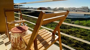 Een balkon met uitzicht op een stadsgezicht, een houten stoel en een trommel.