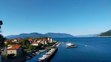 Un pueblo costero con un puerto deportivo, casas con techos rojos y montañas al fondo.
