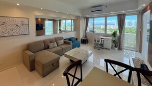 A modern living room with a sofa, a dining table, and a desk. - La Mirada Residences spaces Sea-view Suites (Lapu-Lapu)