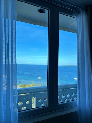 A window with a view of the sea and a boat. - La Mirada Residences spaces Sea-view Suites (Lapu-Lapu)