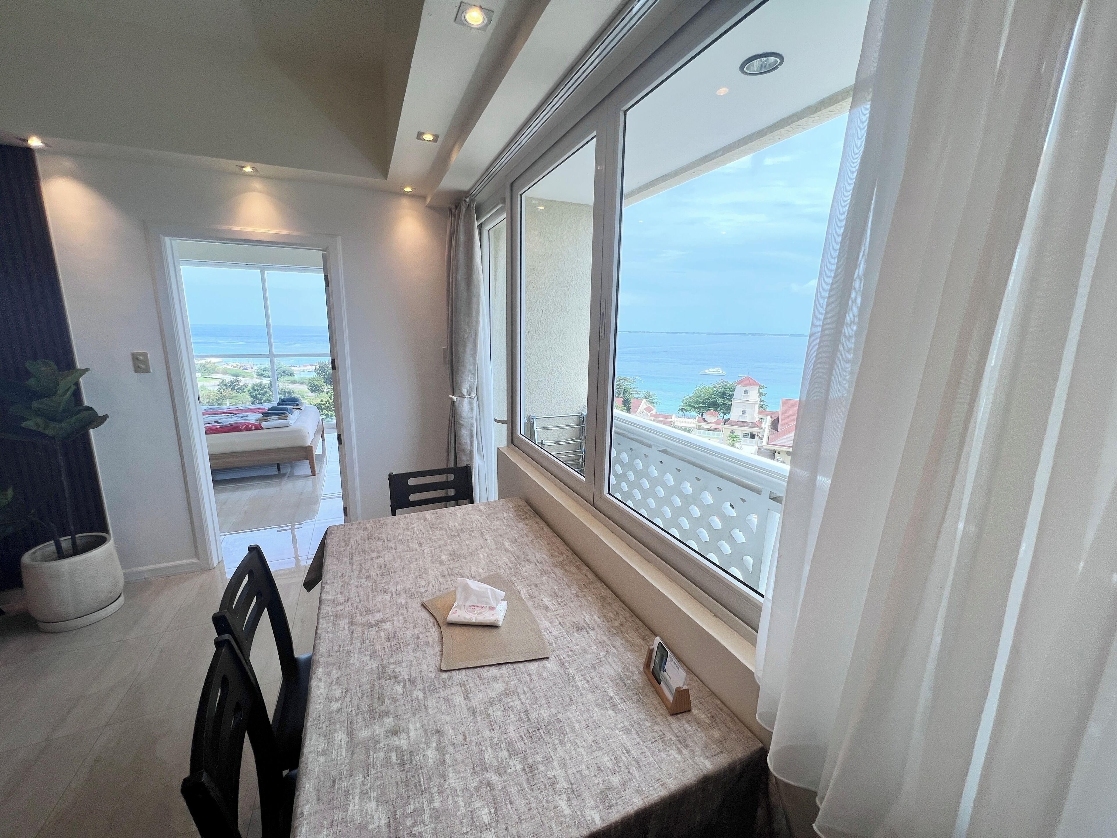 A balcony with a view of the sea, a table with a tissue box, and a chair.