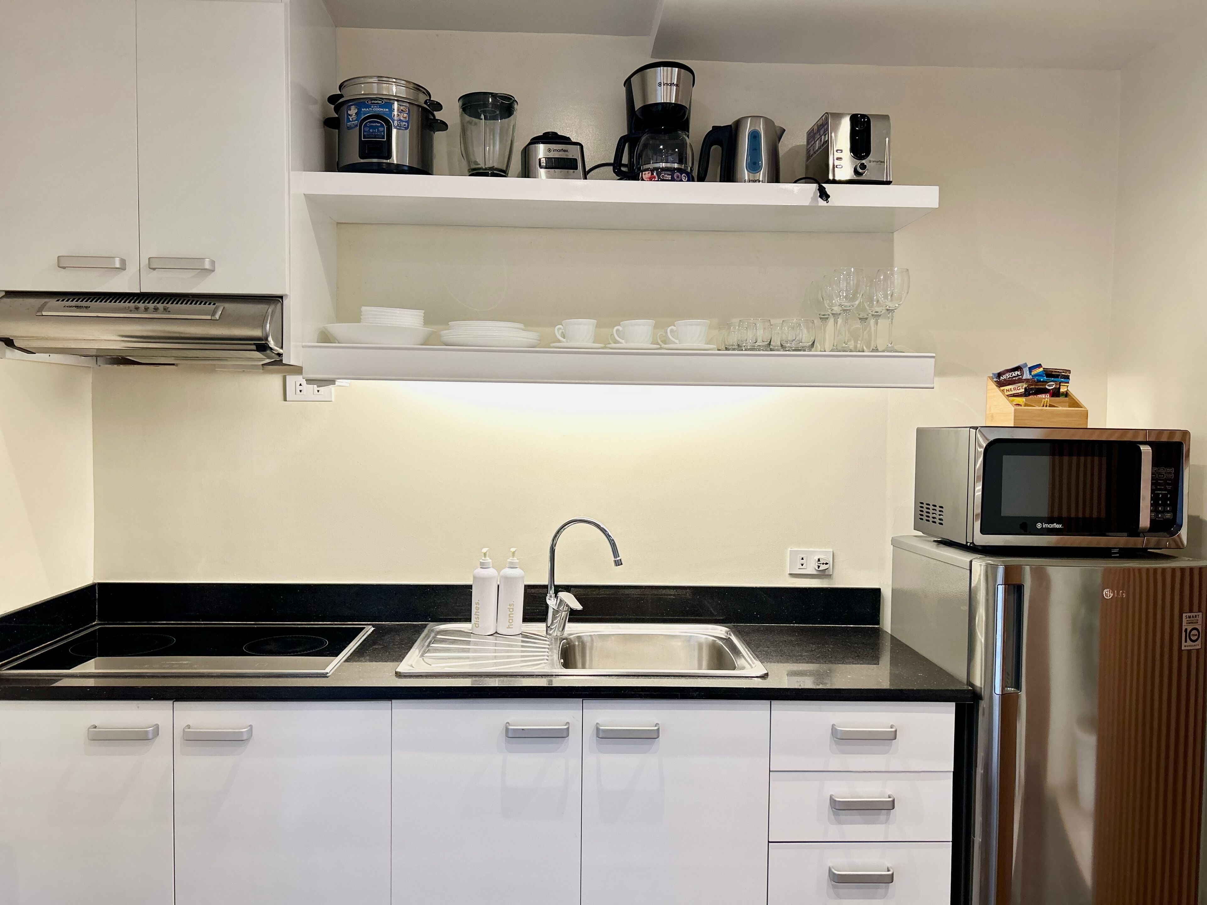 Une cuisine moderne avec des meubles blancs, un évier en acier inoxydable et un four à micro-ondes posé sur le plan de travail.