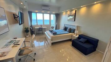 Habitación de hotel moderna con cama, escritorio, silla y vista al mar.