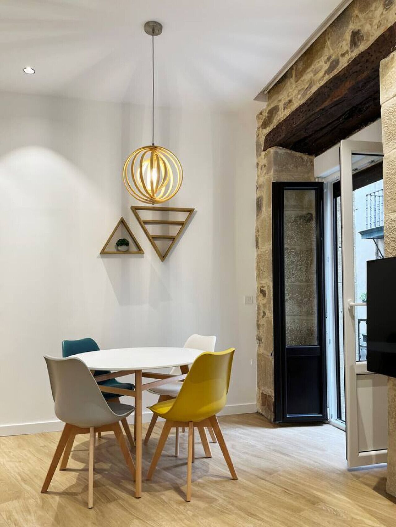 Un espace repas moderne avec une table blanche, quatre chaises et un luminaire suspendu original.