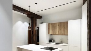 Une cuisine moderne dotée d’un îlot central, de tabourets en bois et d’une cuisinière intégrée.