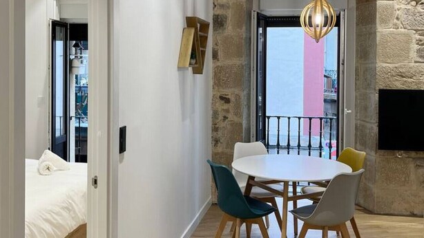 Een moderne eetruimte met een accentmuur van steen, een ronde tafel en stoelen.