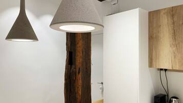Una cocina moderna con una viga de madera, armarios blancos e iluminación colgante.