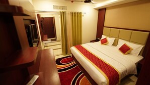 Habitación de hotel con cama, escritorio, silla, ventilador de techo y ventana con cortinas.