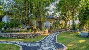 Un jardín ajardinado con un sendero serpenteante, bordes de piedra y árboles maduros.