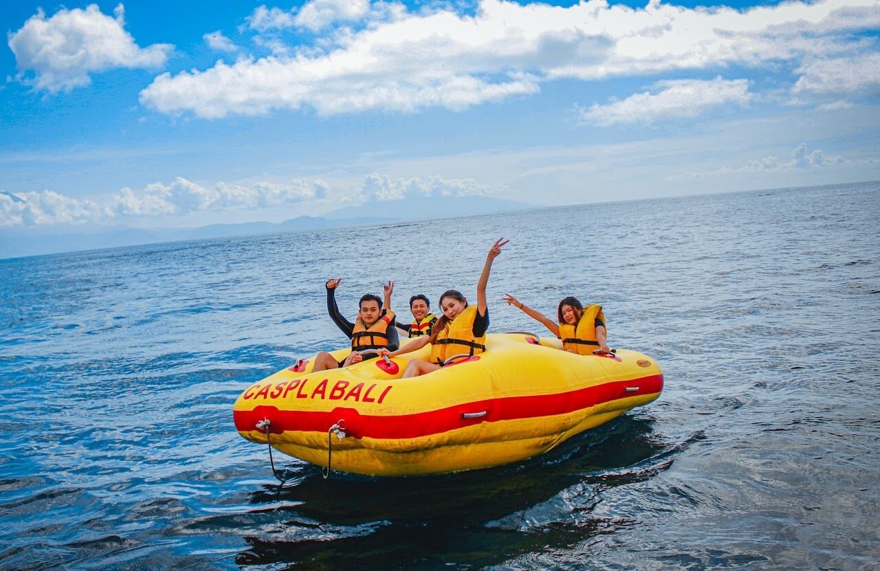 A group of people on a yellow inflatable raft labeled "CASPLABALI" on the water.