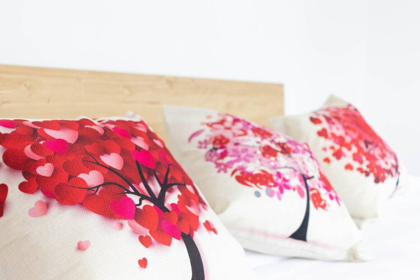 Un lit avec trois oreillers ornés de motifs en forme de cœur et d’arbres.