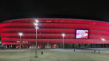 Un estadio con fachada roja y una gran pantalla digital que muestra un logotipo.