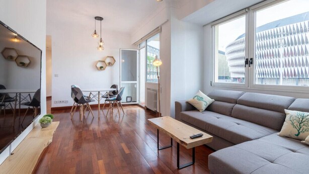 A modern living room with a sofa, a coffee table, and a dining area with chairs and a table.