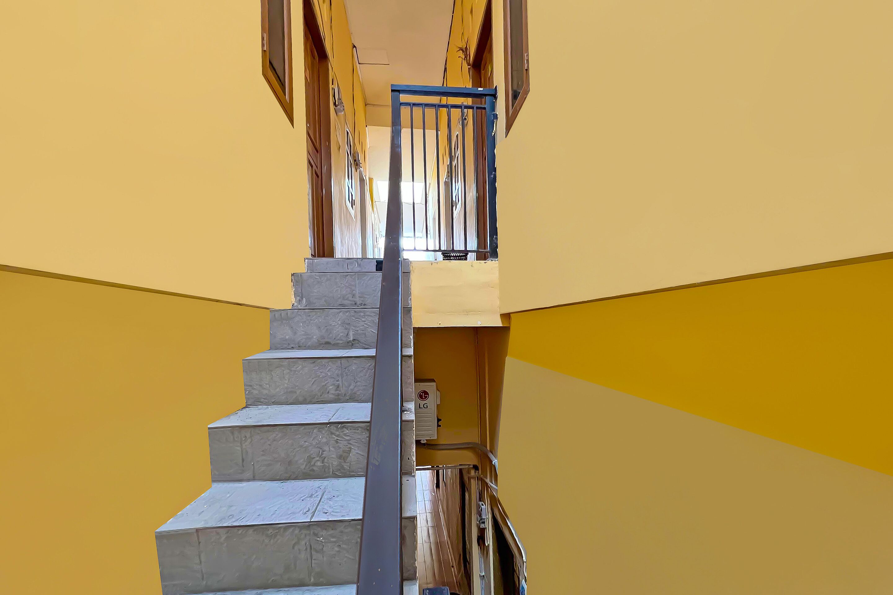 A concrete staircase with a metal handrail, leading to a landing with a door and a small electrical box.