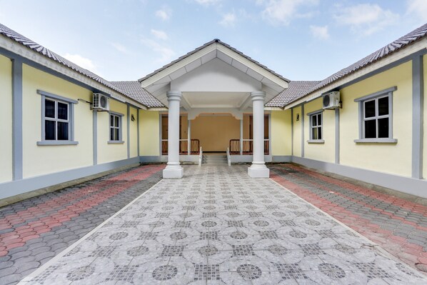 A building with a symmetrical facade, a central covered walkway, and a tiled floor.