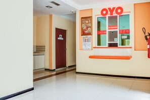 A hallway with a reception desk labeled "OYO," a fire extinguisher, and a door marked "AR RAUDHAH."