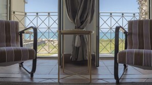 Un balcón con dos sillas a rayas, una mesita y vista al mar.