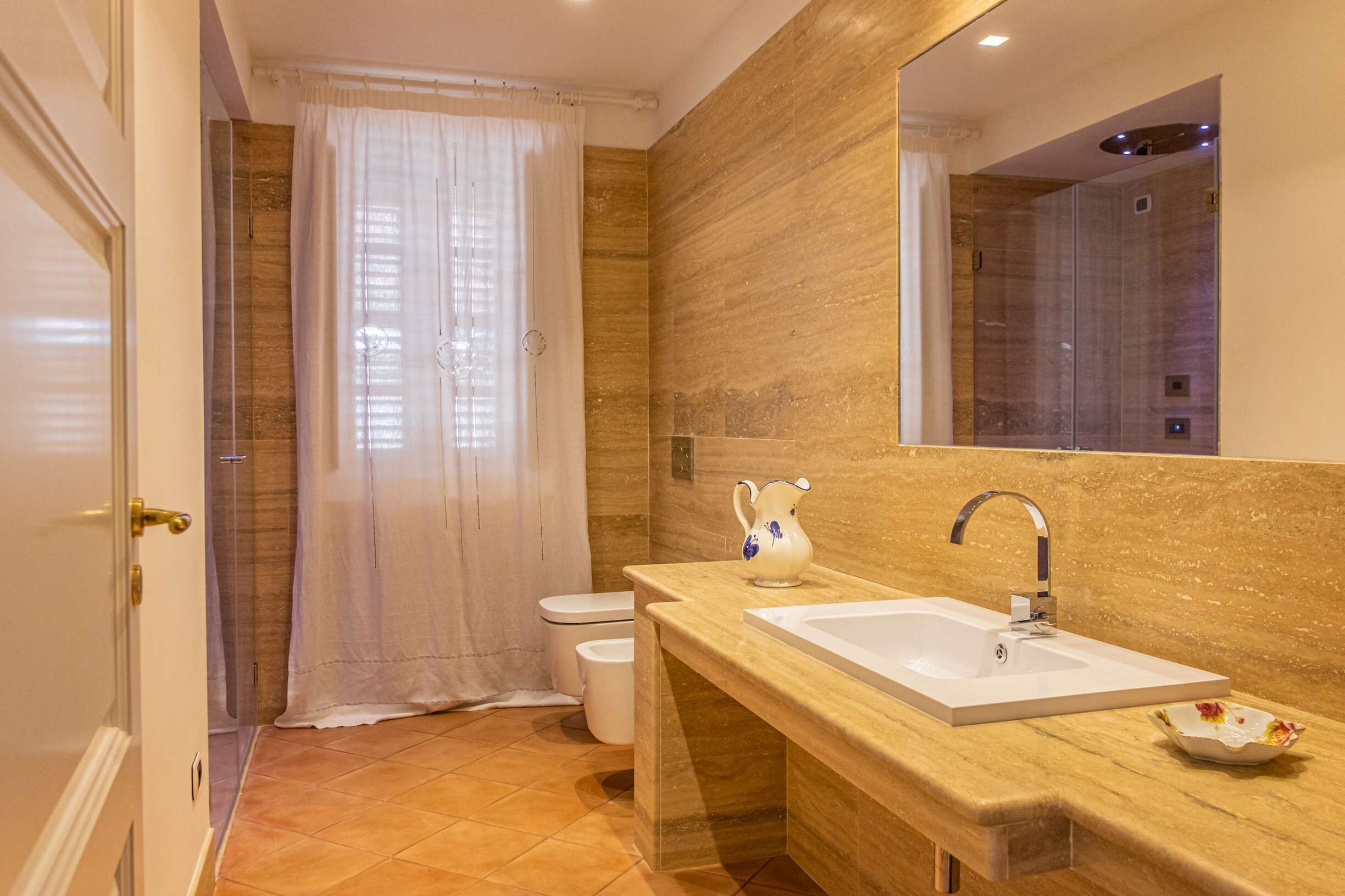 Ein modernes Badezimmer mit großem Spiegel, Waschbecken und Dusche.