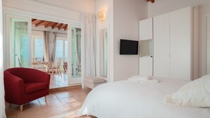 Un dormitorio con una cama grande, un televisor montado en la pared y una silla roja.